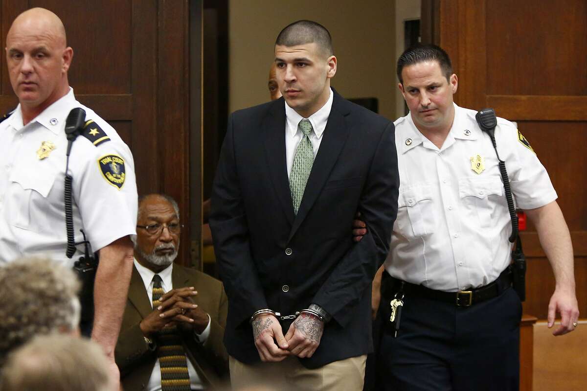 Former New England Patriots tight end Aaron Hernandez is led into the courtroom to be arraigned on homicide charges at Suffolk Superior Court in Boston, Wednesday, May 28, 2014. Hernandez pleaded not guilty in the shooting deaths of Daniel de Abreu and Safiro Furtado. He already faces charges in the 2013 killing of semi-pro football player Odin Lloyd.