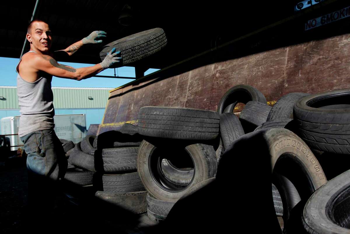 R.J, a temporary Liberty Tire Recycling employee, loads used tires on to the conveyer belt which will transport tires into the recycling process at Liberty Tire Recycling on Friday, Nov. 16, 2012, in Baytown. Liberty Tire Recycling is the largest tire processor in the country that shreds half of all the tires people discard every year, but they are now going to face competition from a new Houston plant that promises a cleaner, more modern recycling process. ( Mayra Beltran / Houston Chronicle )