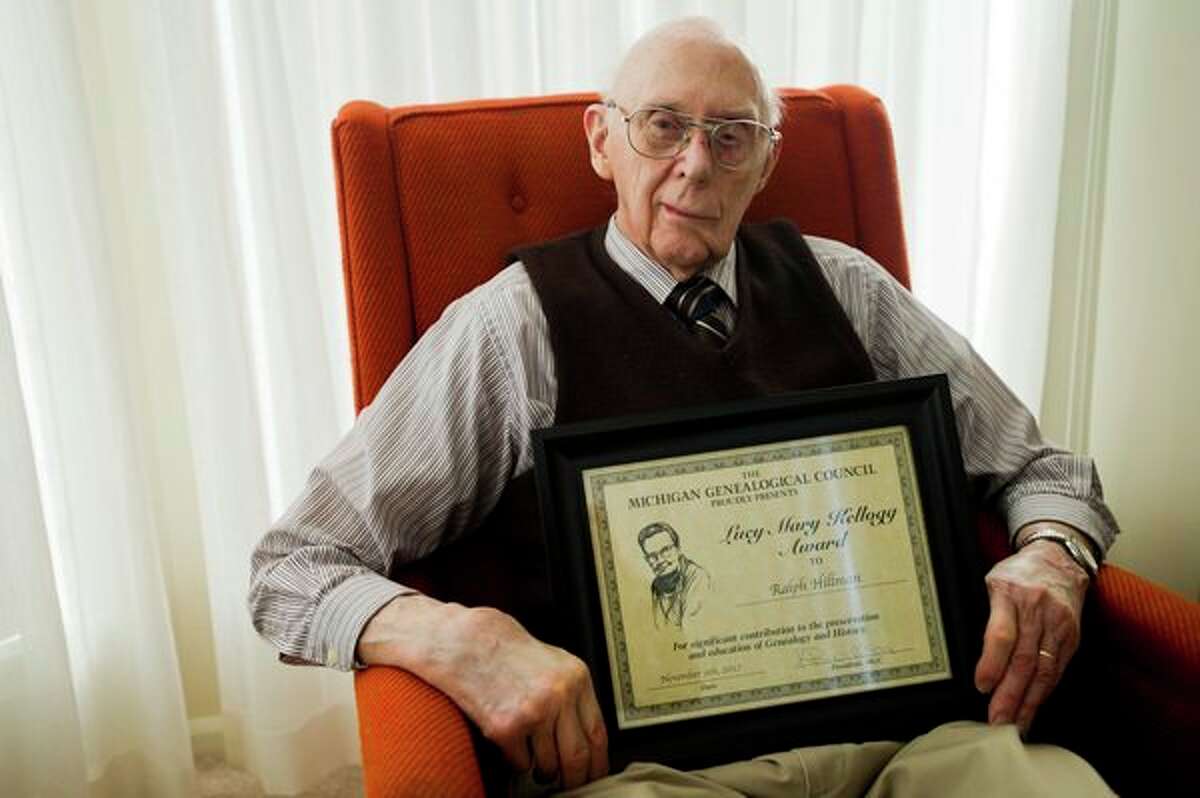 Ralph Hillman poses for a portrait in his apartment on Tuesday with a plaque he received when he was awarded the Lucy Mary Kellogg Award from the Michigan Genealogical Council. (Katy Kildee/kkildee@mdn.net)