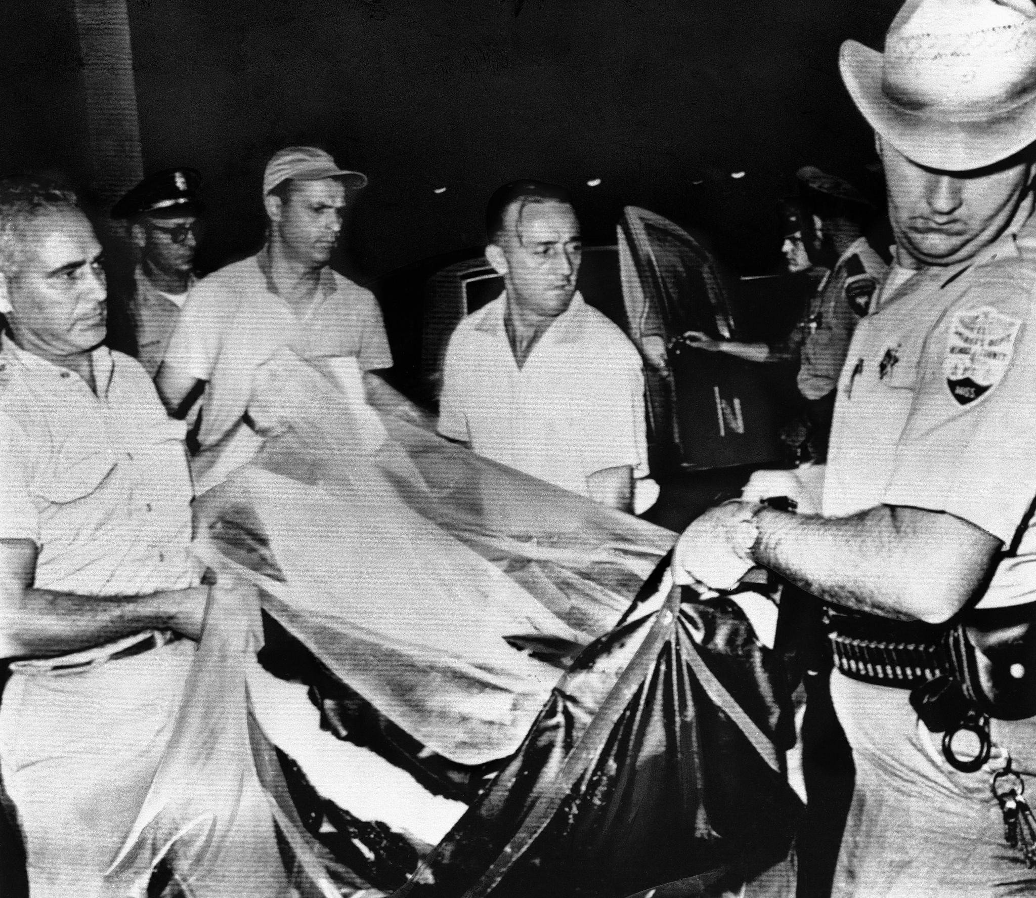 This was the scene last on August 5, 1964 when Neshoba County (Miss.) deputy Sheriff Cecil Price, right, helped unload body of one of three civil rights workers at Jackson, Miss. Bodies earlier that day were found in shallow graves near dam site near Philadelphia, Miss. Price today was one of 21 persons arrested by the FBI in connection with the slayings. (AP Photo)
