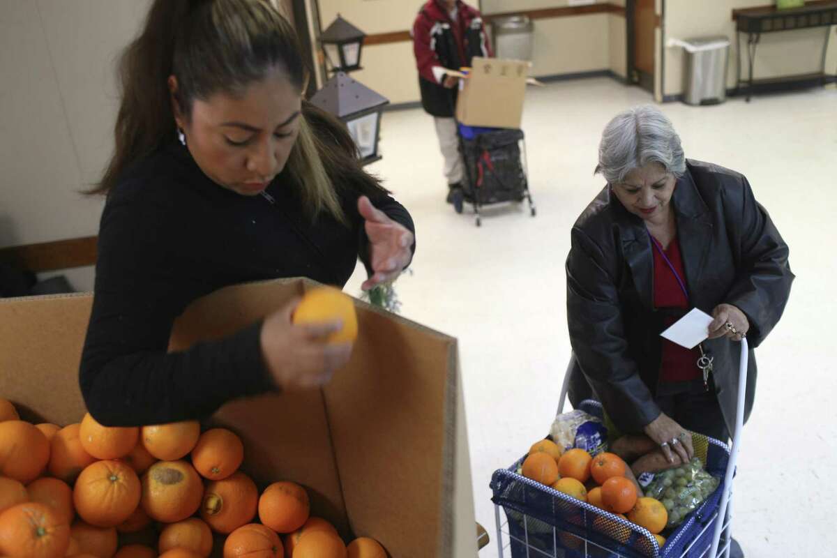 Michelle Cruz, 42, hands Angelita Elizondo, 68, oranges at the Last Chance Ministries Bread of Life Food Pantry Dec. 13, 2017. San Antonio has been ranked No. 1 in economic segregation.
