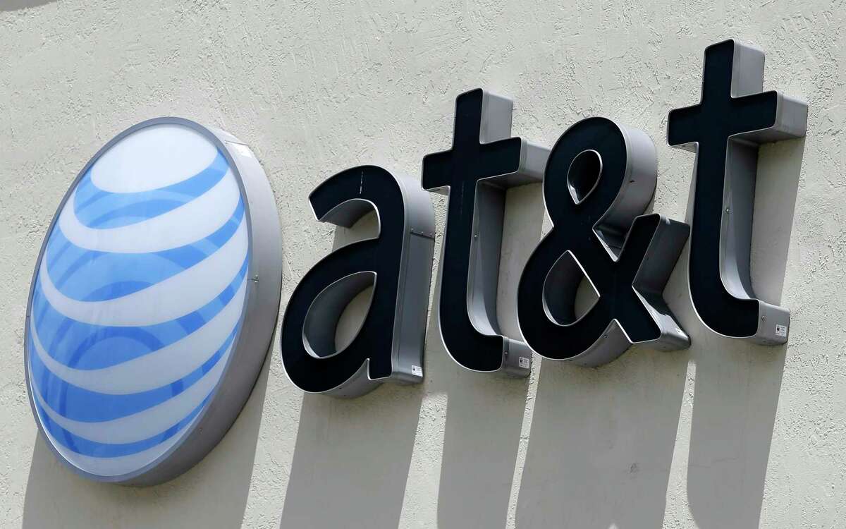 FILE - This Thursday, July 27, 2017, file photo shows an AT&T logo at a store in Hialeah, Fla. Dozens of companies, including AT&T, have announced they are giving their employees bonuses, following the passage of the Republican tax plan that President Donald Trump signed into law in December. (AP Photo/Alan Diaz, File)