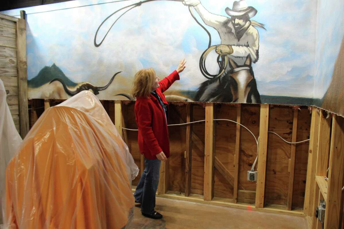 Butler Longhorn Museum director Monica Hughes shows a mural that was partially destroyed in August by flooding from Hurricane Harvey. The museum has been closed for repairs ever since.