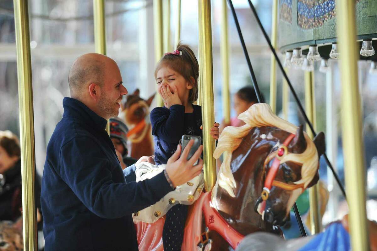 Three-year-old Ruby Tello shares a laugh with her father Craig while riding the Mill River Park Carousel in downtown Stamford, Conn. on Sunday, Jan. 14, 2018.