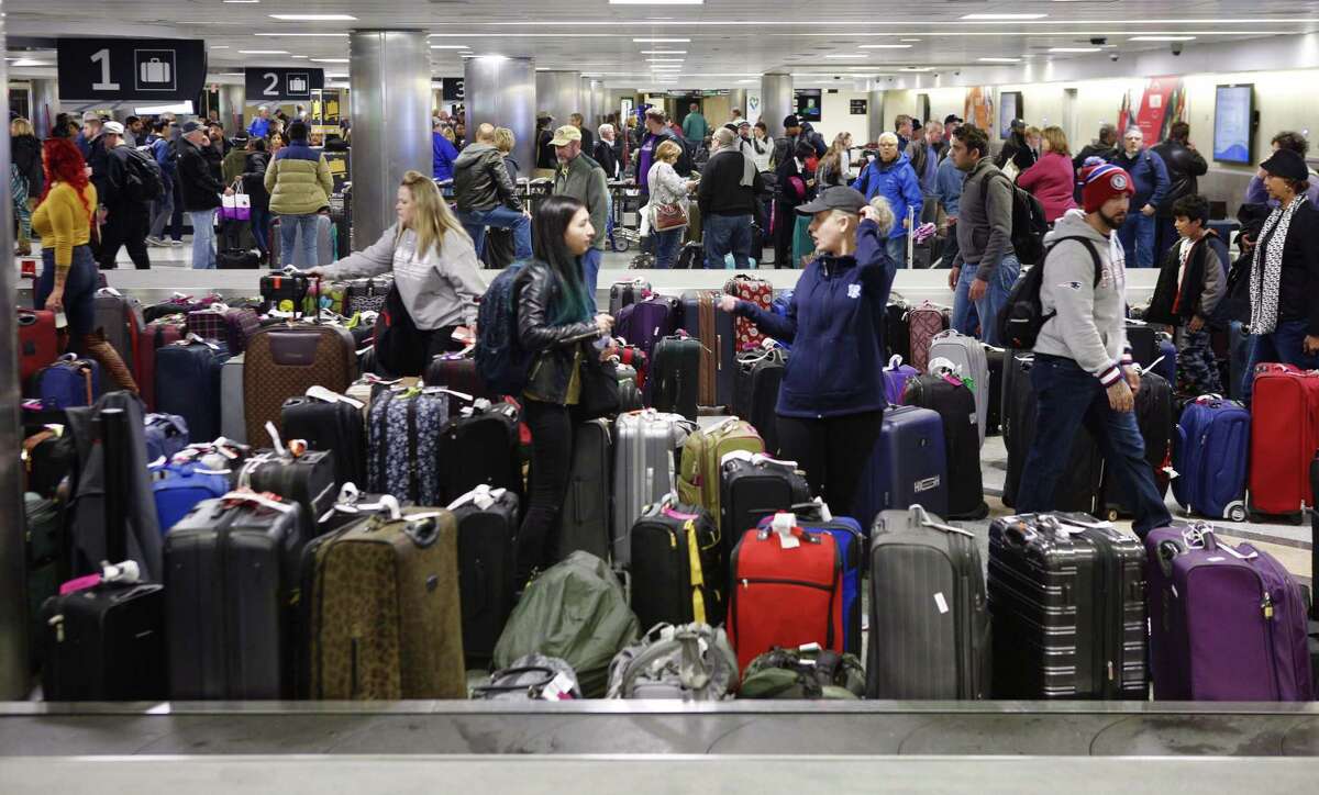 Passengers pick up bags from cancelled flights in the baggage claim at Hobby Airport, January 16, 2018, in Houston.