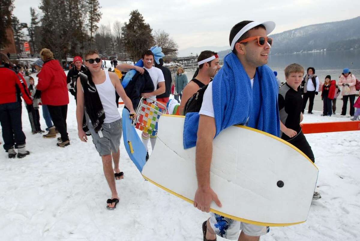 Nick Barone of Averill Park, right, leads his surfer friends, including Tom Probst, left, and Tom Cooley, center, to the beach Friday for the annual Lake George Winter Carnival's First Day Polar Plunge in Lake George Village. (Cindy Schultz / Times Union)