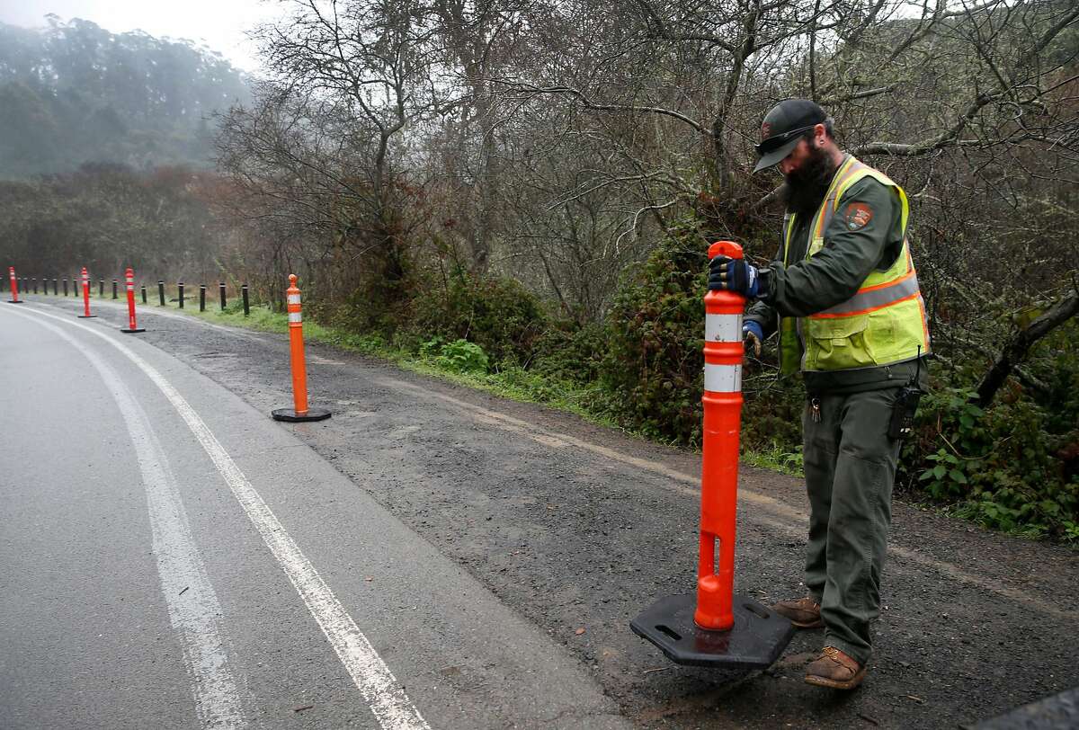 Danny Dixon places temporary barricades to restrict parking along Franks Valley Road on the first day of a reserved parking system at Muir Woods National Monument in Mill Valley, Calif. on Tuesday, Jan. 16, 2018.