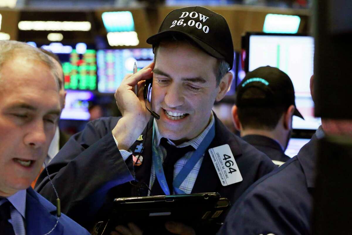Trader Gregory Rowe, center, wears a "Dow 26,000" hat as he works on the floor of the New York Stock Exchange, Tuesday, Jan. 16, 2018. The Dow Jones industrial average traded above 26,000 for the first time. (AP Photo/Richard Drew)