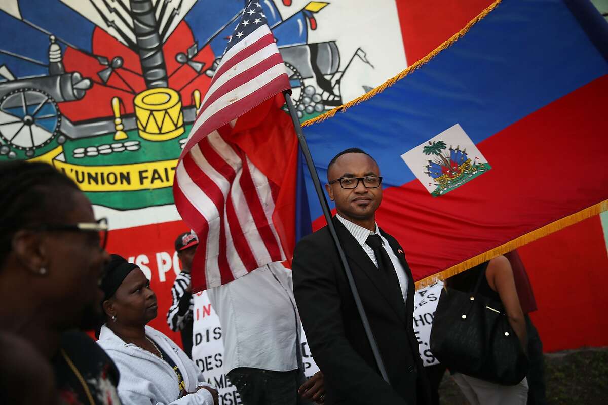 Fandzy Bernadin holds an American flag as he joins with others to mark the 8th anniversary of the massive earthquake in Haiti and to condemn President Donald Trump's reported statement about immigrants from Haiti, Africa and El Salvador on January 12, 2018 in Miami, Florida.