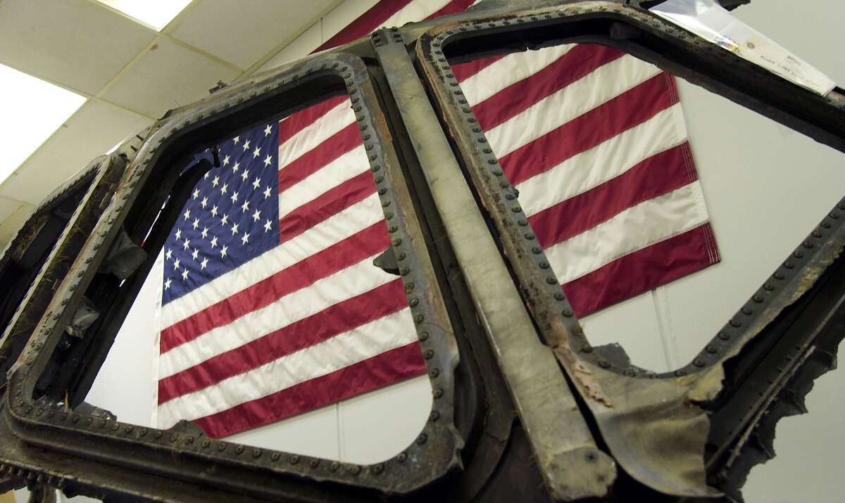 KENNEDY SPACE CENTER, FLORIDA - JANUARY 30: A U.S. flag hangs behind the cockpit windows from the Space Shuttle Columbia January 30, 2004 at Kennedy Space Center in Florida. The remnents, which were open to the news media on January 30, will be stored on the 16th floor and will be available for research. (Photo by Matt Stroshane/Getty Images)