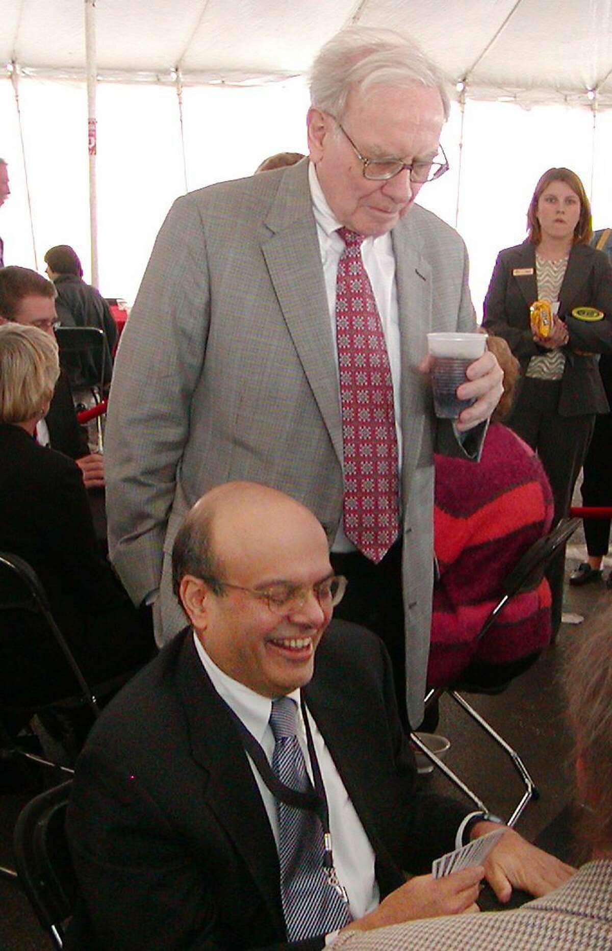 Warren Buffet, chairman and chief executive officer of Berkshire Hathaway Inc., looks over the shoulder of Ajit Jain, head of the reinsurance unit with Berkshire Hathaway Inc.,