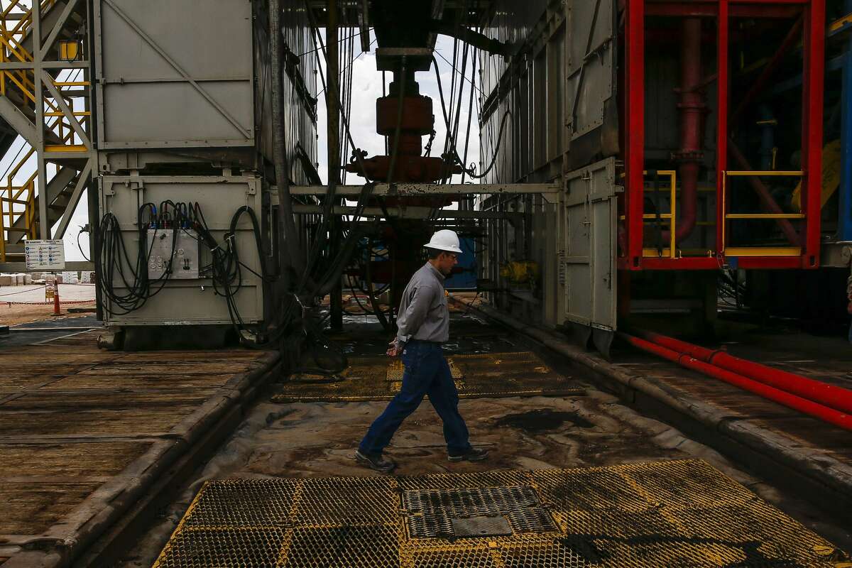 FILE PHOTO: A worker walks across a pad site where a drilling rig will create three to six wells next to each other at a Chevron drilling and hydraulic fracturing.