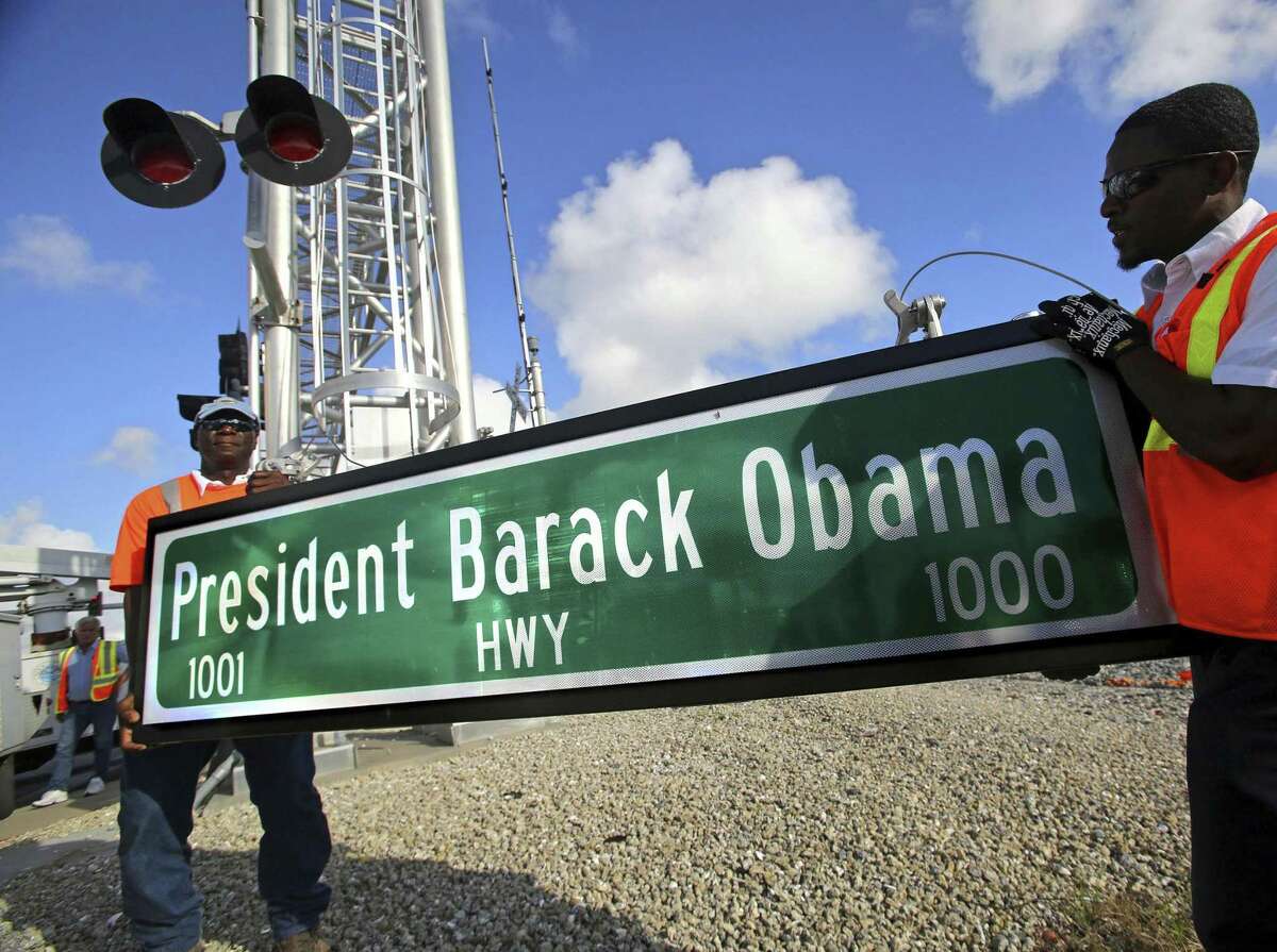 FILE - In this Thursday, Dec. 17, 2015 file photo, Dale Moncur, left, and Cedric Anderson of Palm Beach County Traffic Operations, hold a sign for the new President Barack Obama Highway in preparation to change it from the "Old Dixie Highway" in Riviera Beach, Fla. On Friday, Jan. 5, 2018, The Associated Press reported that stories circulating on the internet about President Donald Trump ordering the name of the highway changed back to ?“Old Dixie?” are untrue. (Lannis Waters/Palm Beach Post via AP)