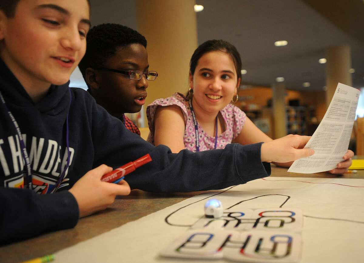 From left; Sixth graders Justin Zarra, 12, Jason Hutchinson, 11, and Lily Banks, 11, experiment with an Ozobot programmable robot for the first time during library learning time at Perry Hill School in Shelton on Tuesday, January 16, 2018. The robot has sensors that respond to specific color codes causing it to speed up, slow down, and change direction.