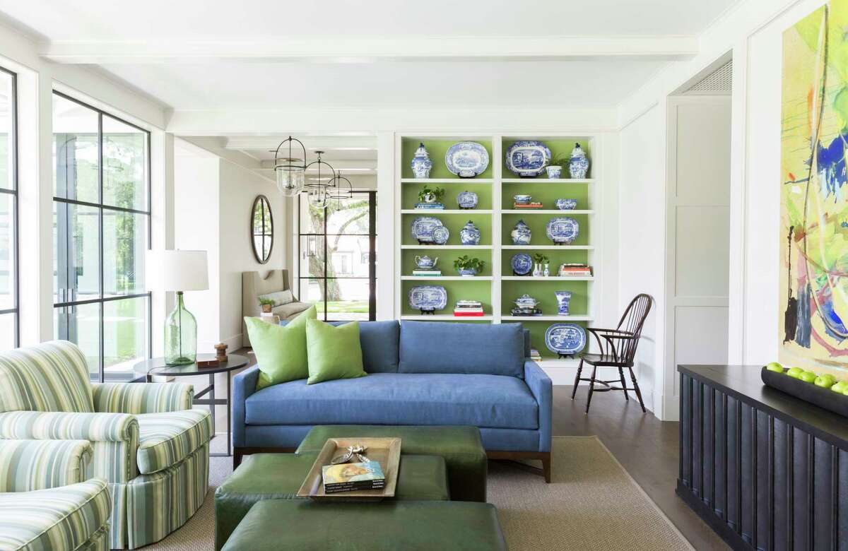 The adults' family room - no toys allowed - in the Tanglewood home of Lucy and Fowler Carter features statement abstract art and shelving backed in a lovely green color that makes blue-and-white pottery pop.