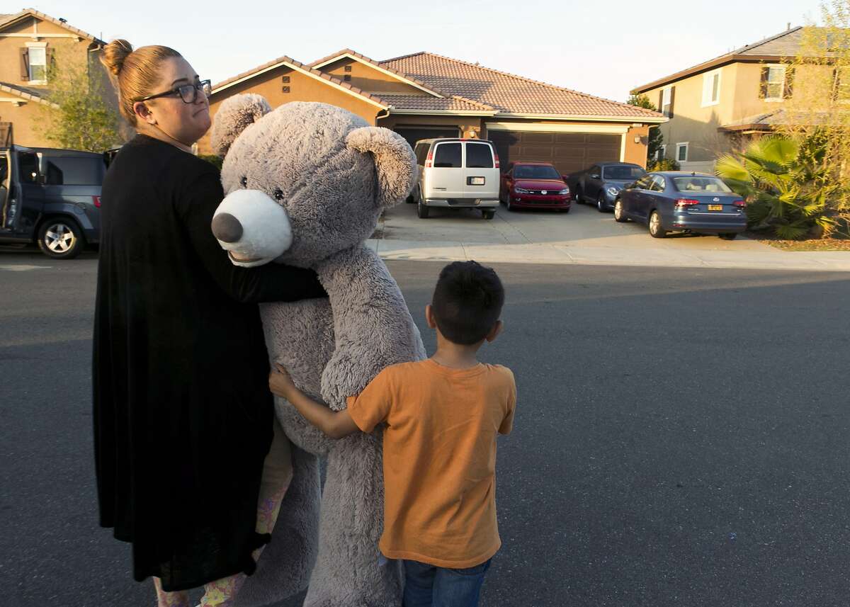 In this Thursday, Jan. 18, 2018, photo neighbors, Liza Tozier and her son Avery Sanchez, 6, drop off his large "Teddy" as a gift for the children who lived on a home where police arrested a couple on Sunday accused of holding 13 children captive in Perris, Calif. Psychological experts say 13 children rescued from what was described as nothing less than a torture chamber will have years of therapy ahead as they learn to live in a world that, until a week ago, they never really knew existed. Authorities say the children of David and Louise Turpin of Perris, Calif., were confined to the house, chained to furniture and starved. (AP Photo/Damian Dovarganes)