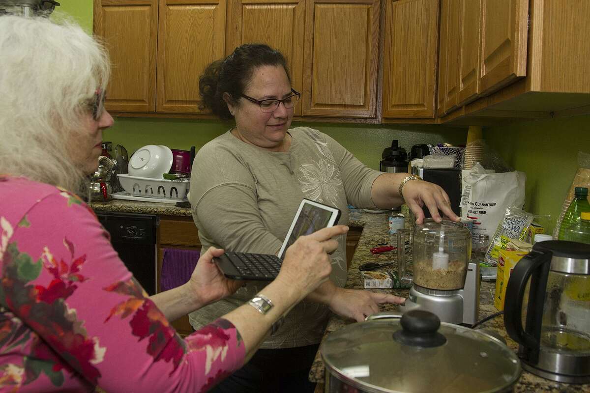 Michelle Newman, left, uses her iPad to record Marina Lang chopping nuts as she helps make the Pakistani dessert sheer khurma. Lang is originally from Brazil and previously taught a class in Brazilian cuisine at the Raindrop Turkish House.