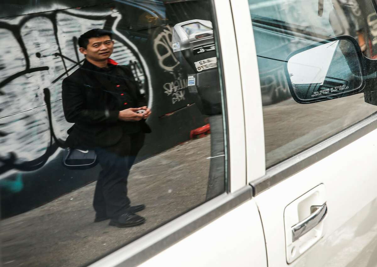 Magician Dan Chan is seen reflected in a parked car Tuesday, Jan. 16, 2018 on Golden Gate Avenue in San Francisco, Calif. near where his car was broken into and his magic back was stolen in August.