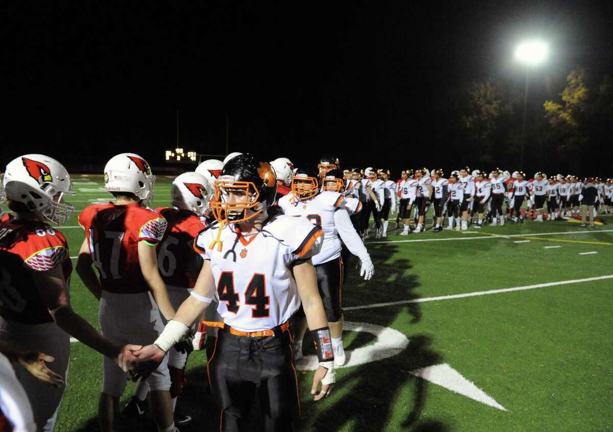 The Ridgefield High School football team, right, shakes hands with the Greenwich High School football at the end of the game under the lights at Cardinal Stadium in Greenwich, Conn., Saturday, Nov. 4, 2017. Greenwich remained undefeated winning the game 26-21 over Ridgefield.