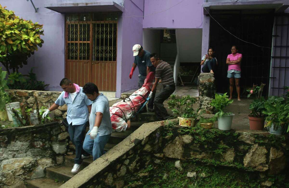 FILE - In this Aug. 29, 2017 file photo, a body wrapped in a bloodstained sheet is removed from an apartment building where a woman and two men were executed, in the Alta Progreso neighborhood of Acapulco, Mexico. Both men were bound with tape, and all three were shot in the head at an apartment outfitted as an office for a taxi service. Mexico's Interior Department posted on Sunday, Jan. 21, 2018 that the country's homicide rate is the highest in decades. (AP Photo/Bernandino Hernandez, File)