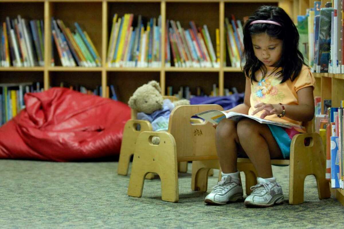 Rubab Khan, 4, reads a book in the childrens section at the Albany Public Library last week. ( Michael P. Farrell / Times Union )