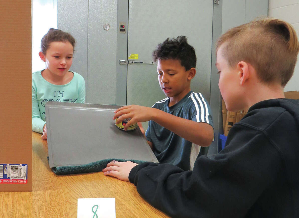 Thijson, center and Jacob D. right, demonstrate their experiment to Lilly L. during the fifth-grade Science Fair at Trinity Lutheran School. Students up to fourth grade were invited to the gymnasium to view the fifth graders’ work.