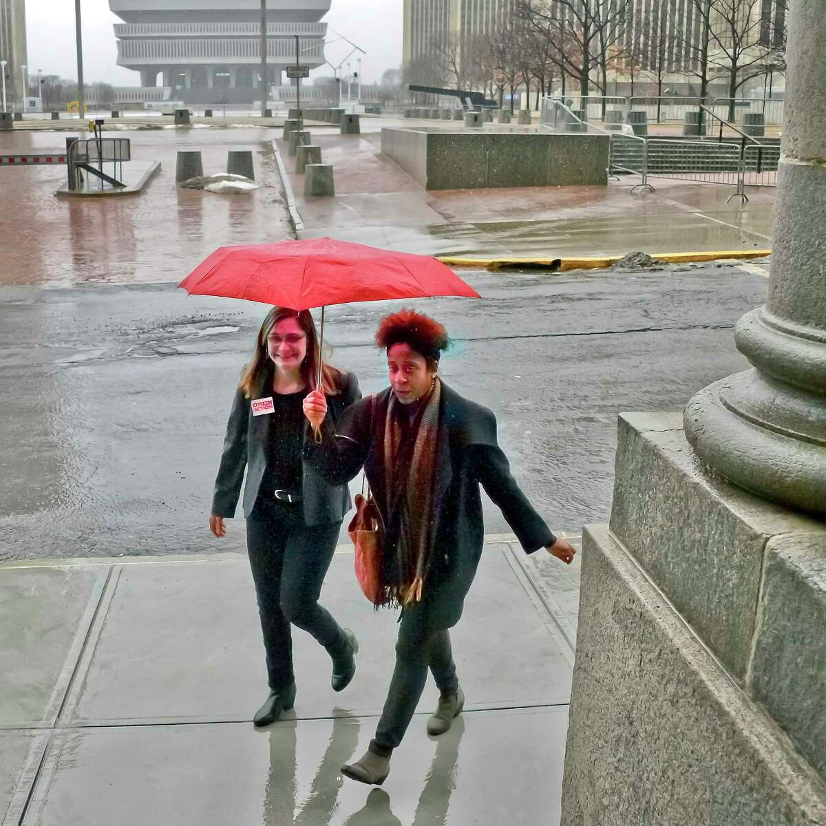 Jess Wisneski, left and Janel Quarless share an umbrella on their way to a voting rights rally at the Capitol Tuesday Jan. 23, 2018 in Albany, NY. (John Carl D'Annibale/Times Union)