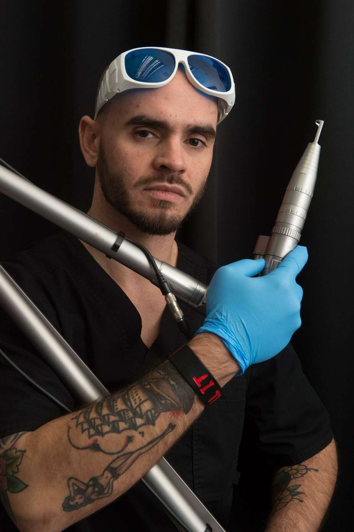 Zack Wells, a certified laser specialists at the MEDermis Laser Clinic, poses with one of the lasers he uses to remove no-longer-loved tattoos.