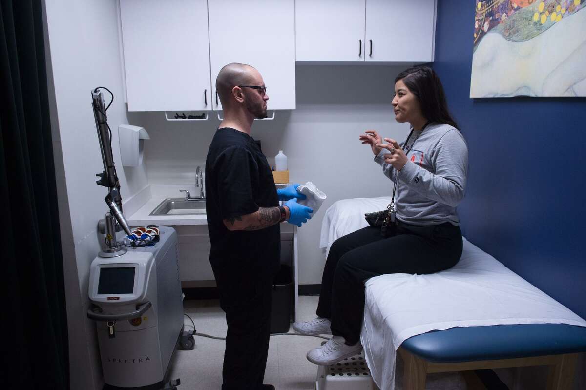 Wells consults with client Monica Muñoz prior to a tattoo removal session.