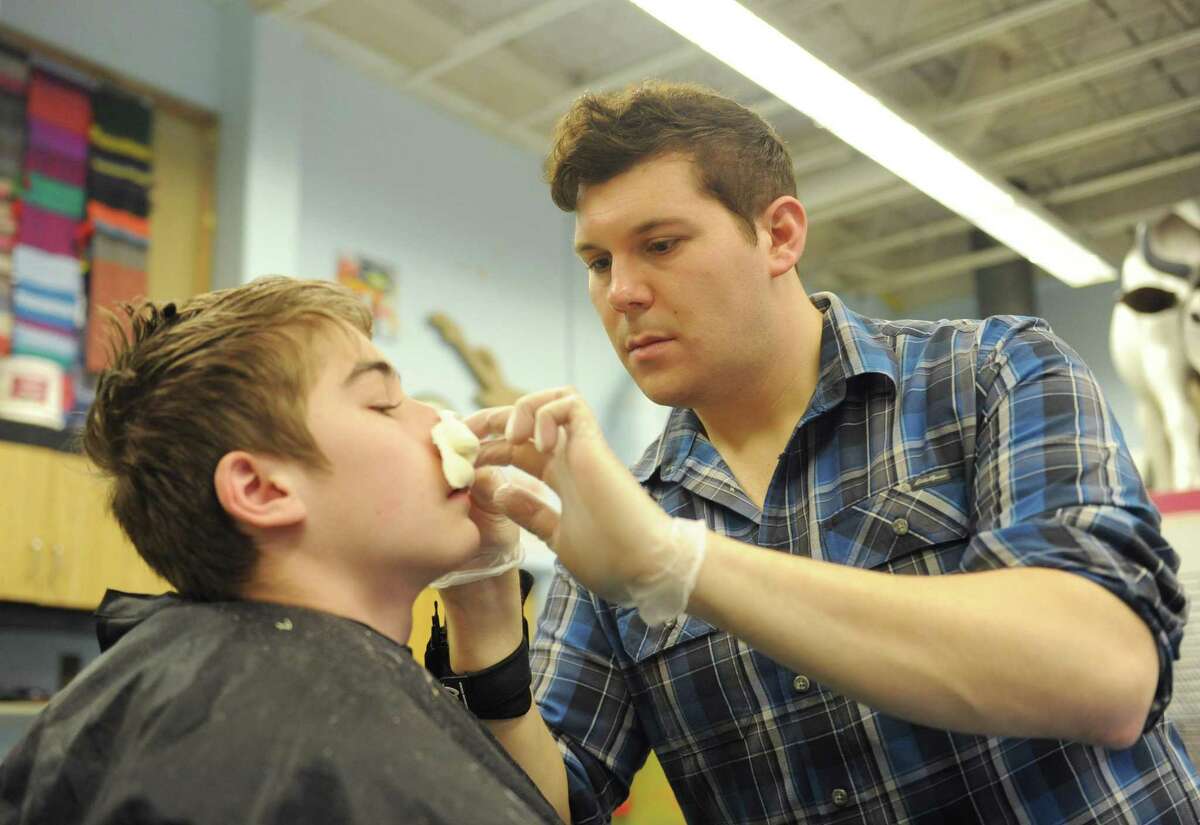 Makeup artist Tyler Green, of Litchfield, puts a prosthetic nose of eighth-grader Ashton Monteiro during a special effects makeup demonstration at Eastern Middle School in the Riverside section of Greenwich, Conn. Tuesday, Jan. 23, 2018. Green, a finalist on Syfy's "Face Off" SFX makeup reality show, gave demos transforming students into whimsical characters with the application of facial prosthetics and makeup.