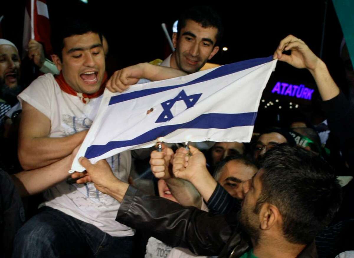 Friends and family members of Turkish activists who were deported by Israel two days after a deadly naval raid by Israeli forces in the Mediterranean Sea, set on fire an Israeli flag as they wait at Ataturk Airport in Istanbul, Turkey, early Thursday, June 3, 2010. Hundreds of activists deported from Israel following a bloody raid by Israeli commandos on a pro-Palestinian flotilla returned to a hero's welcome in Turkey early Thursday. (AP Photo/Ibrahim Usta)
