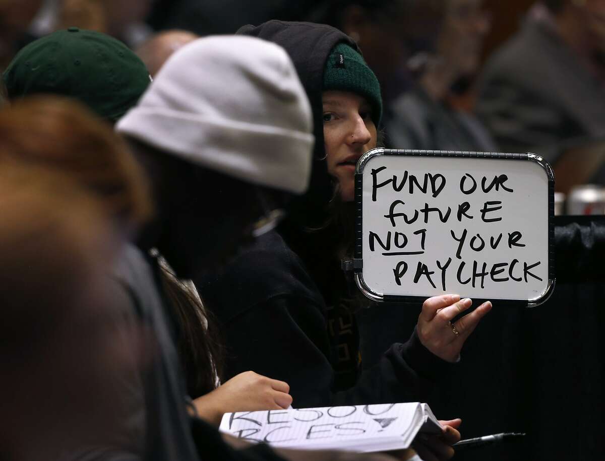UC Santa Cruz student Katherine Wethington holds a white board to display a message at a meeting of the UC Board of Regents in San Francisco, Calif. on Wednesday, Jan. 24, 2018 where a tuition increase is being considered.