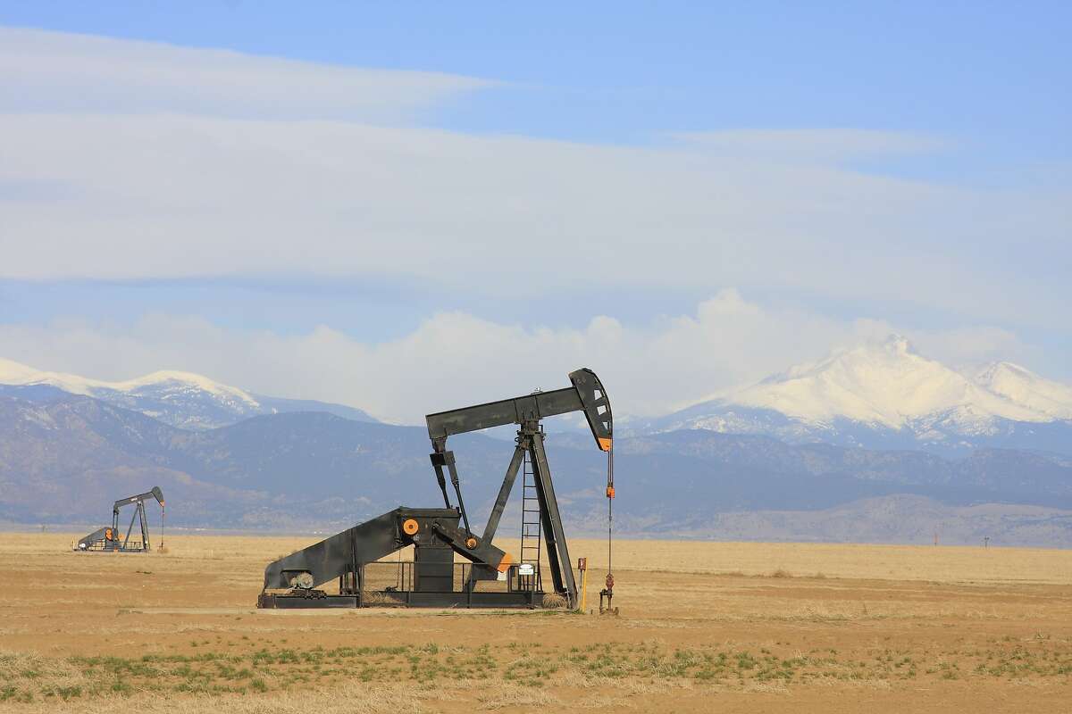 A Pumpjack pumping oil from an oil well in the plains with snow capped mountains in the backgroud. oil wells, industry, gas, gasoline, pump, mountains, plains, pumpjack, nodding donkey, pumping unit, horsehead pump, borehole, fuel, natural gas, crude, crisis, beam pump, rod pump, grasshopper, thirsty bird, jack pump, drilling, gusher, production, petroleum, reserve