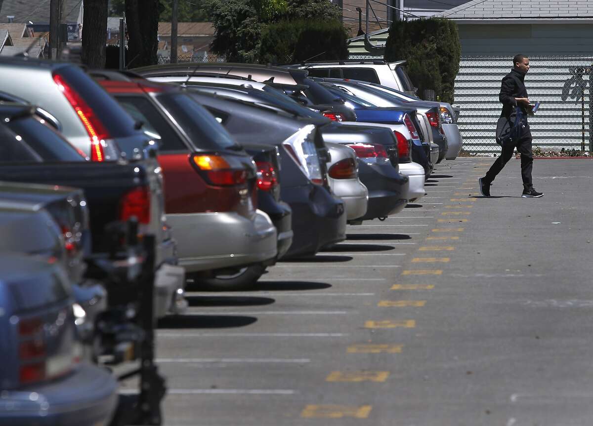 FILE-- A commuter walks to the Coliseum station after finding a space in a BART parking lot in Oakland on Thursday, April 30, 2015. BART officials are looking at overhauling their parking policies to allow prices that increase or decrease depending on demand and using license-plate readers to determine who’s paid for a space and who gets a citation.