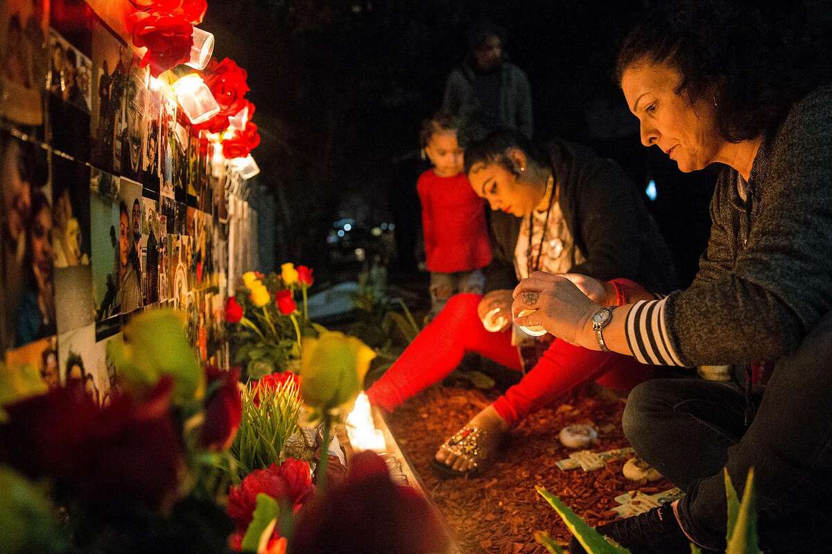Alicia Saddler, center, and Annice Evans light candles for a vigil in front of their house remembering their brother and son Angel Ramos, who was shot and killed by Vallejo Police, Tuesday, Jan. 23, 2018 in Vallejo, Calif.