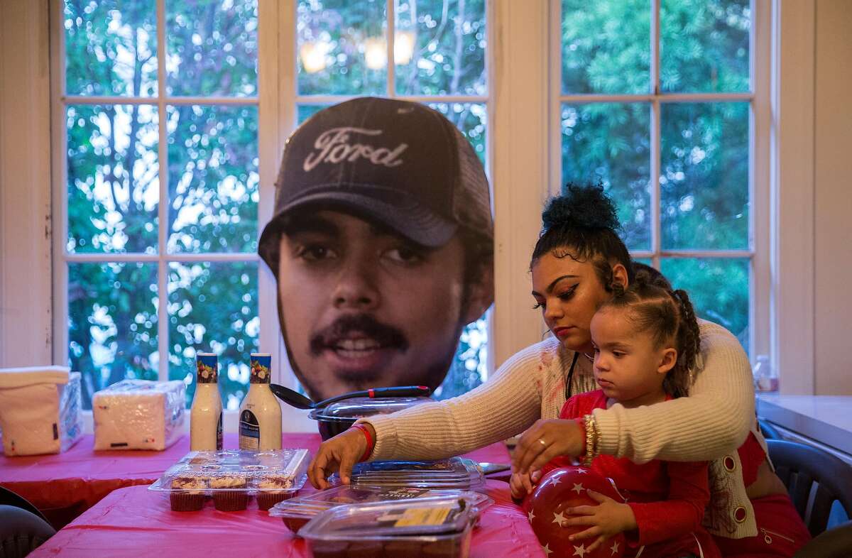Alicia Saddler, sister of Angel Ramos who was shot and killed by Vallejo Police, holds her daughter, Khloe, 3, while sitting near a cut-out of Angel's face in their family dining room Tuesday, Jan. 23, 2018 in Vallejo, Calif.