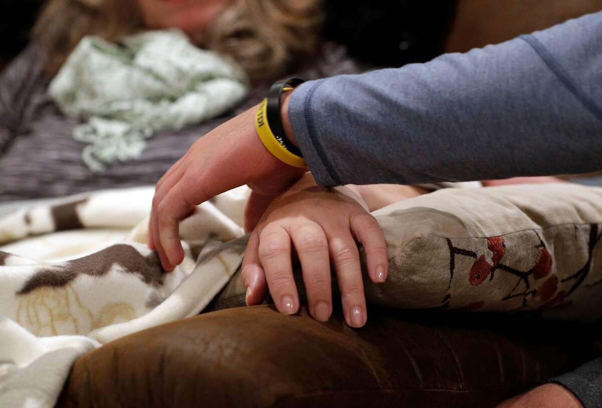 Austin Piscotty, Stephen Piscotty's youngest brother, adjusts his mother's hand on a pillow when she was uncomfortable while in their home in Pleasanton, Calif., on Monday, January 22, 2018. Stephen Piscotty, who was raised in the East Bay a die hard A's fan, was traded from the St. Louis Cardinals to the A's in the offseason. The move has brought him home an opportune time, as his mother Gretchen was recently diagnosed with ALS.