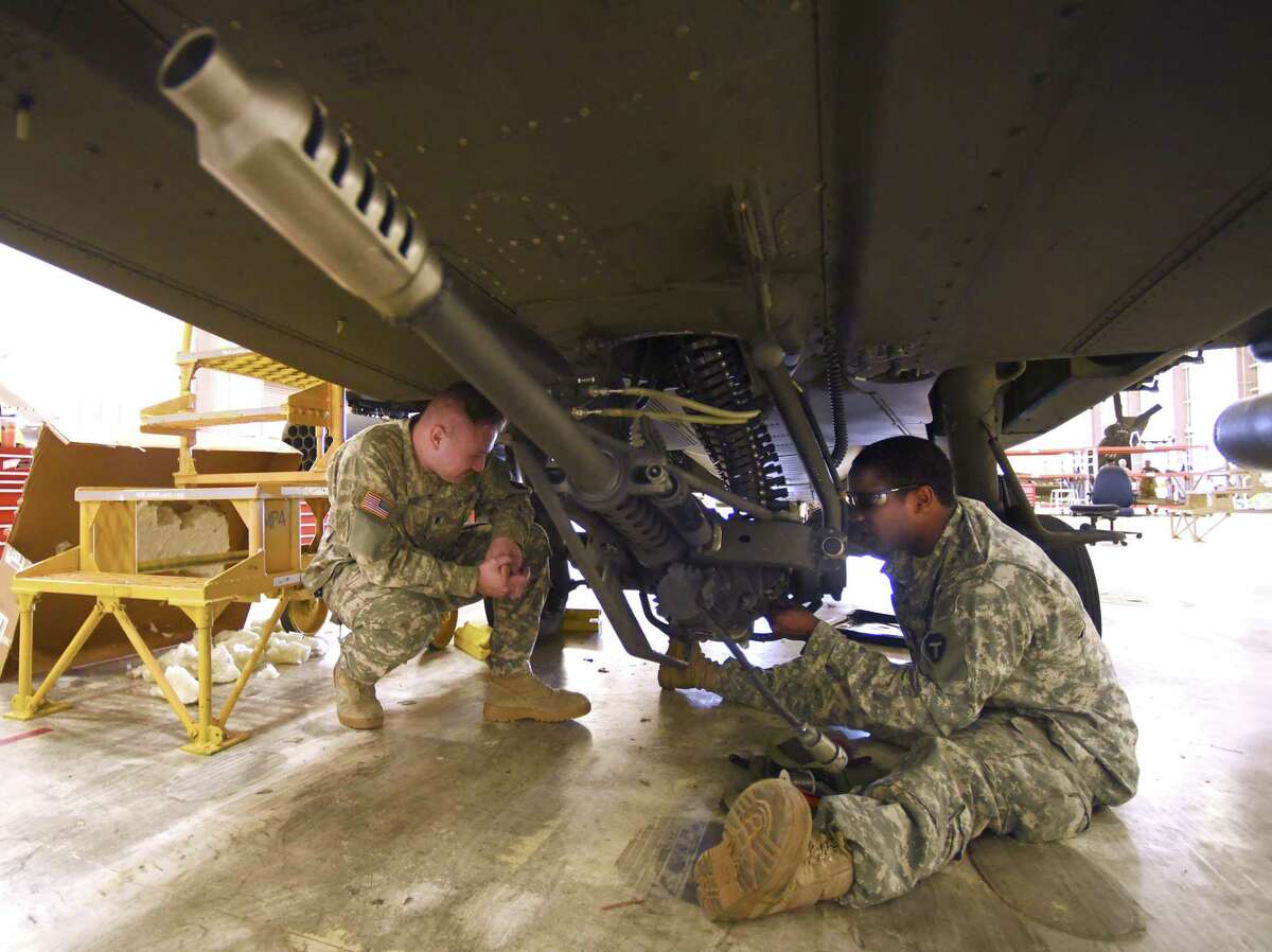 Specialists Conor Yost, left, and Joel Mapps work on the 30mm cannon on a Texas National Guard Apache attack helicopter at Ellington Field on Wednesday, Jan. 24, 2018.