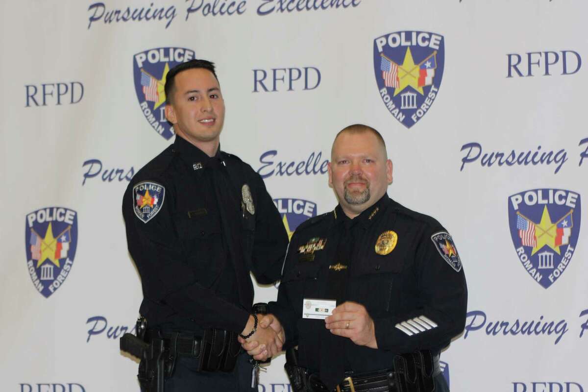 Roman Forest Police Officer of the Year Carlos Herrera (left) receives a pin for his award from Police Chief Stephen Carlisle during an awards ceremony Jan. 22 at the EMCID building in New Caney.