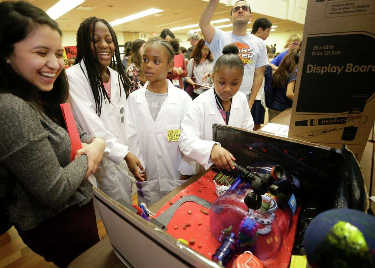 Ana Gonzalez, a University of Houston senior and a competition judge, from left, talks with Blackshear Elementary students Ta'Niyah Cooper, 10, Ja'onna Gray, 10, and Dawana Goodjoint, 9, during the STEM Mars Rover Celebration﻿.