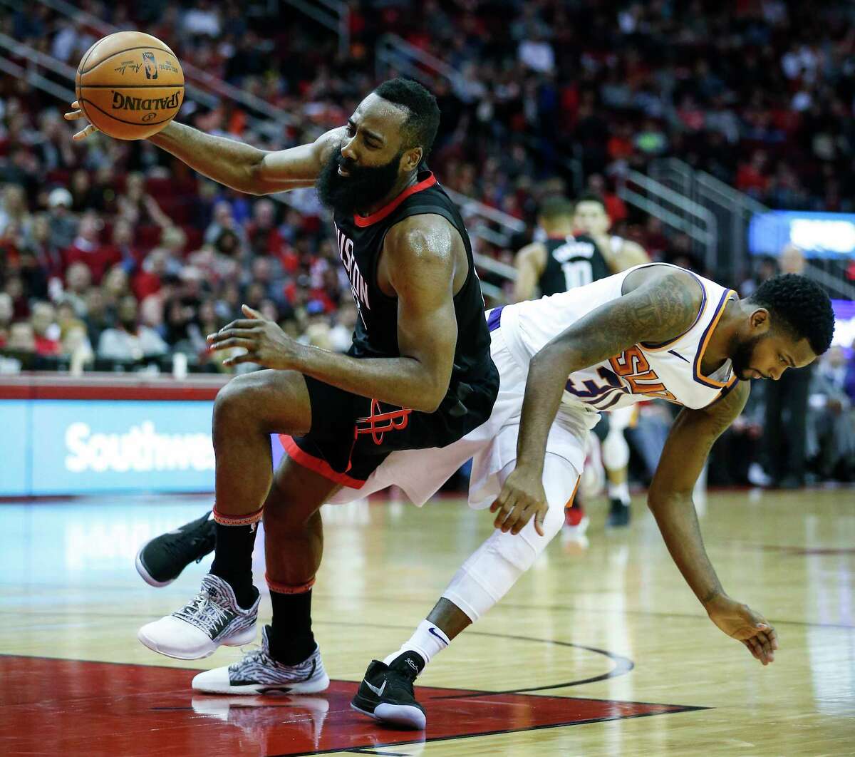 Houston Rockets guard James Harden (13) and Phoenix Suns guard Troy Daniels (30) collide on a pass to Harden during the second quarter of an NBA basketball game at Toyota Center on Sunday, Jan. 28, 2018, in Houston.
