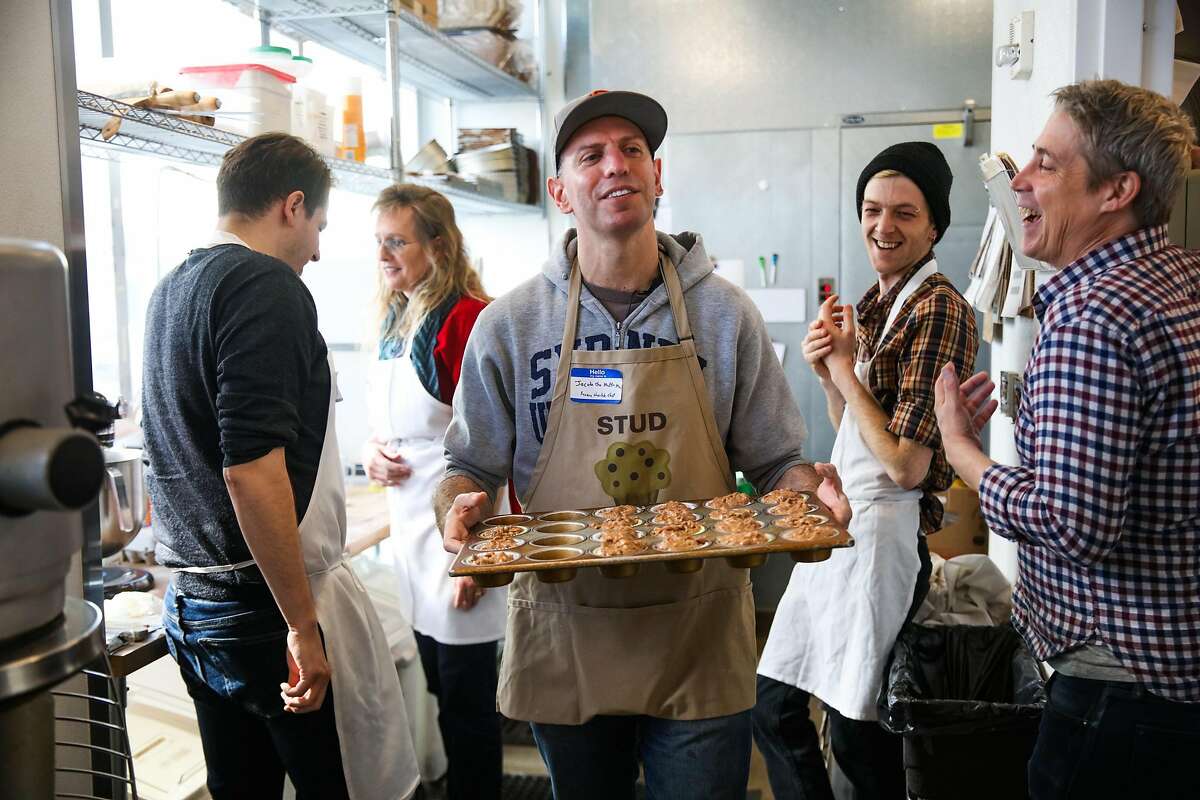 Jacob Kaufman (center) carries a pan of uncooked muffins to the oven while baking muffins for the homeless at Hayes Valley Bakeworks in San Francisco, California, on Sunday, Jan. 28, 2018.