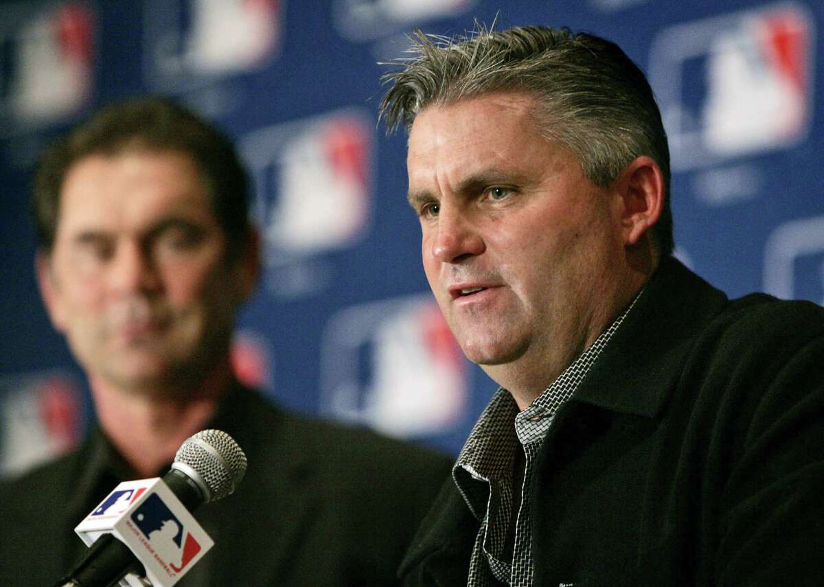 FILE - In this Dec. 7, 2005, file photo, San Diego Padres general manager Kevin Towers, right, peaks during a baseball news conference in Dallas. Towers, whose 14-year tenure as general manager of the San Diego Padres included an appearance in the 1998 World Series, died Tuesday, Jan. 30, 2018, from complications of cancer, friend and former agent Barry Axelrod said. He was 56. (AP Photo/Tony Gutierrez, File)