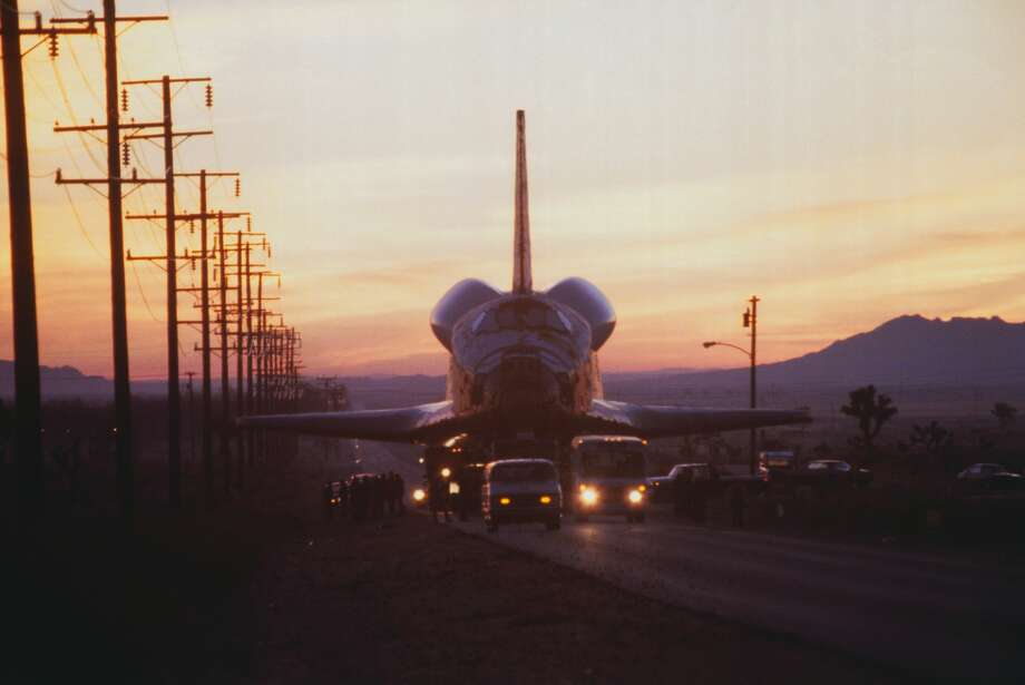 (Original Caption) Palmdale, California: As dawn broke the space shuttle orbiter Columbia was already moving down the road toward Edwards Air Force Base, a 40 mile journey requiring nine hours to negotiate. When Columbia is launched into orbit next November, the spacecraft will be able to circle the Earth in 90 minutes. The shuttle is being taken to Edwards AFB where it will be mounted on a Boeing 747 for the flight to Kennedy Space Center in Florida for the orbital launch. Photo: Bettmann/Bettmann Archive