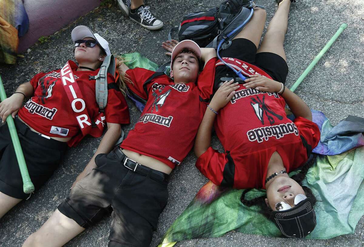 Battle of Flowers 2017: Southside High School flag members Clarissa Cantu (from left), Alejandro Ramirez and Nubia De La Garza lay on the ground after completing the route of the Battle of Flowers parade. With hot temperatures reaching into the mid-90s, the heat wore on participant and spectators throughout the parade.