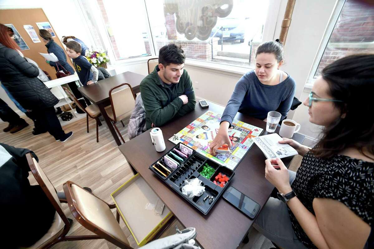 From left, Connor Pineiro and his sisters, Stephanie and Teresa, of Milford play Monopoly Bob’s Burgers at Hawkwood Game Cafe in Milford.