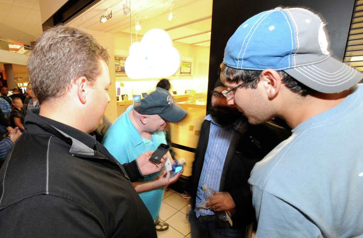 Oliver Bashan, right, one of the first in line for the new iPhone 4S gets a demonstration before his purchase by Nicholas Rust, left, business manager at the Apple store in Crossgates Mall in Albany, N.Y. October 14, 2011. The iPhone 4S was the first iPhone to have Siri preloaded on it. (Skip Dickstein/Times Union)