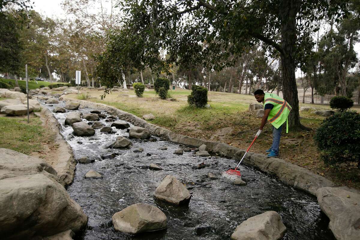 In this Tuesday, Aug. 19, 2014 photo, Jahmal Wilson uses a rake to clean the creek that runs into a lake at Kenneth Hahn State Recreation Area, part of the much larger proposed site of Baldwin Hills Park in the Baldwin Hills section of Los Angeles. he former oil-drilling patch of rolling hills sits along a flood-control channel, but it doesn't provide a drinking water source nor is it part of Southern California�s water-delivery system. Even so, the Baldwin Hills Conservancy stands to gain $10 million if voters approve the $7.5 billion water measure that state lawmakers and Gov. Jerry Brown placed on the November ballot in August 2014 amid the state's historic drought. (AP Photo/Jae C. Hong)