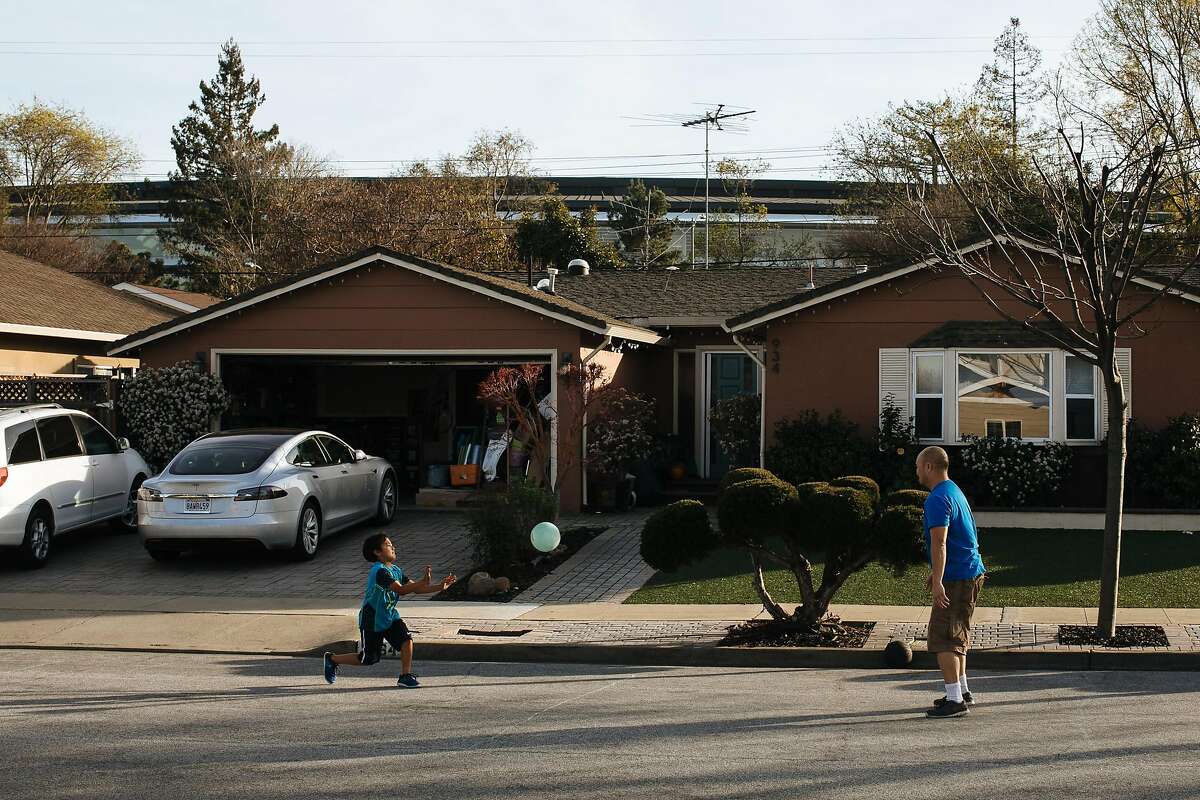Edric Yamamoto and his son, Greyson Yamamoto, 7 play bounce outside their home in the Birdland neighborhood in Sunnyvale, Calif. Wednesday, Jan. 31, 2018. Yamamoto said that he doesn't mind the new Apple campus, which looms over his home.