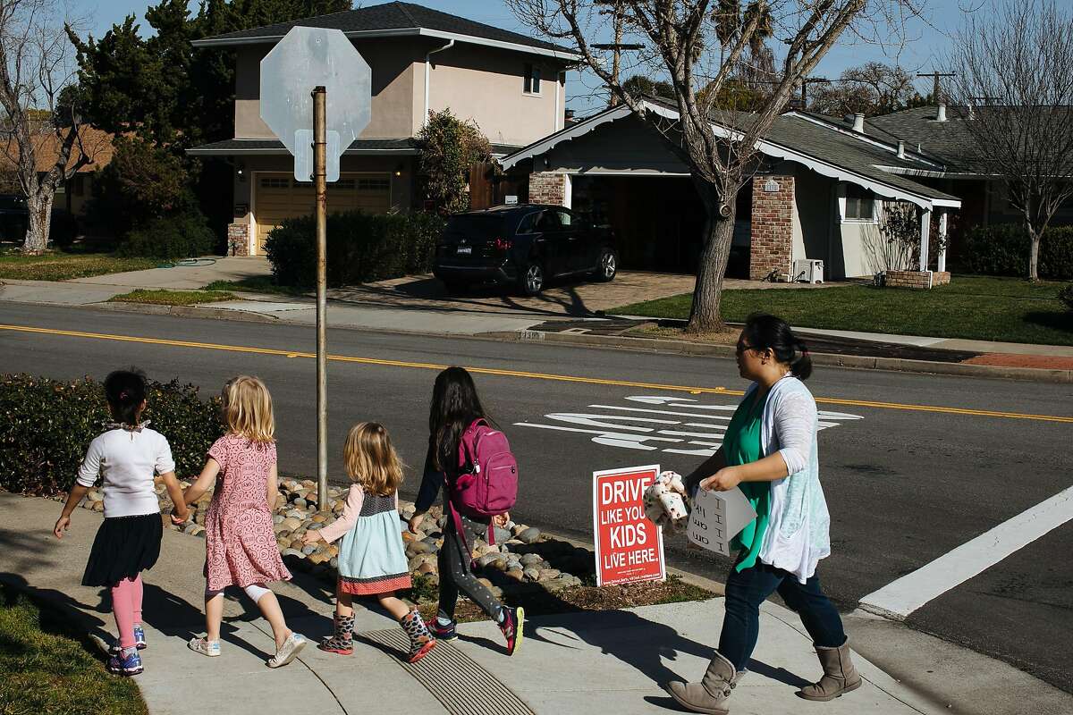 Children walk past a sign that reads "Drive Like Your Kids Live Here" in the Birdland neighborhood in Sunnyvale, Calif. Wednesday, Jan. 31, 2018. With 12,000 workers expected to move into Apple Park, residents have been seeing commuters traffic cut through their neighborhood to avoid the long traffic lights.